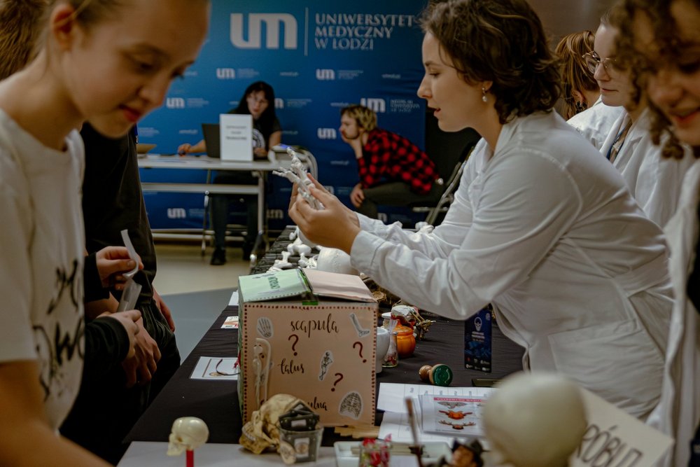 Osoba w białym fartuchu pokazująca model kości