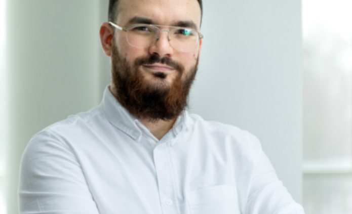 mężczyzna w okularach i z brodą na jasnym tle