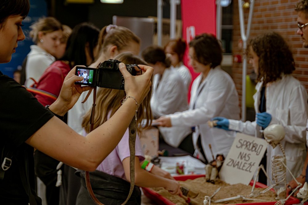 Osoba robiąca zdjęcie członkom koła przy stoisku 
