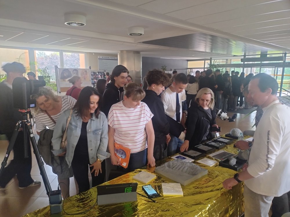 uczestnicy Pikniku naukowego, grupa uczniów i nauczycieli obserwująca stoisko z pokazami fizycznymi