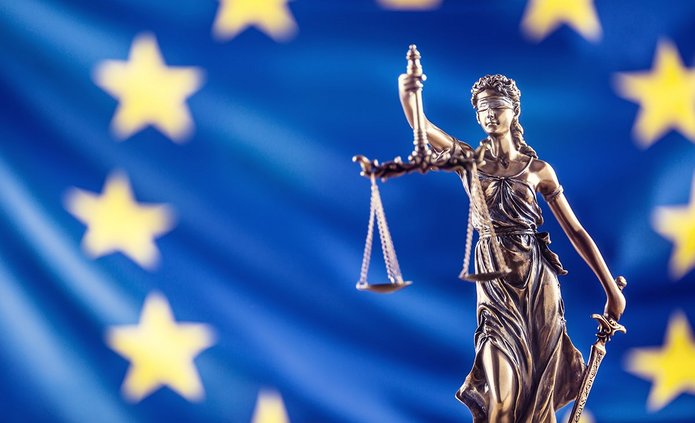 Rzeźba Temidy na tle flagi UE.