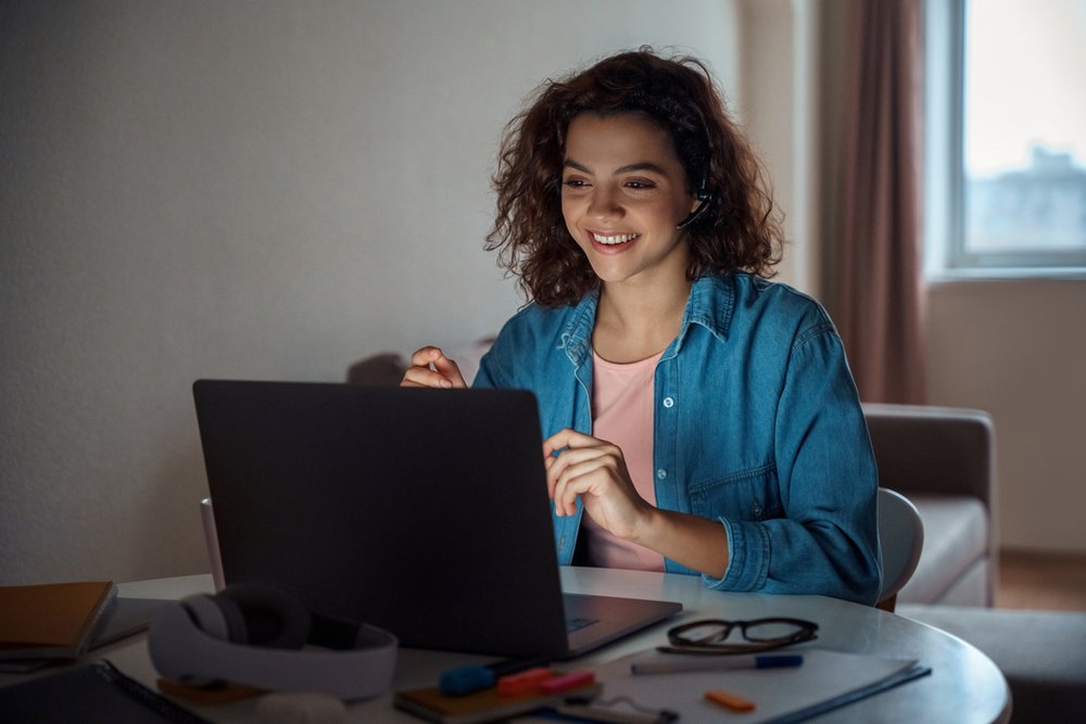 A student is smiling in front of her laptop.