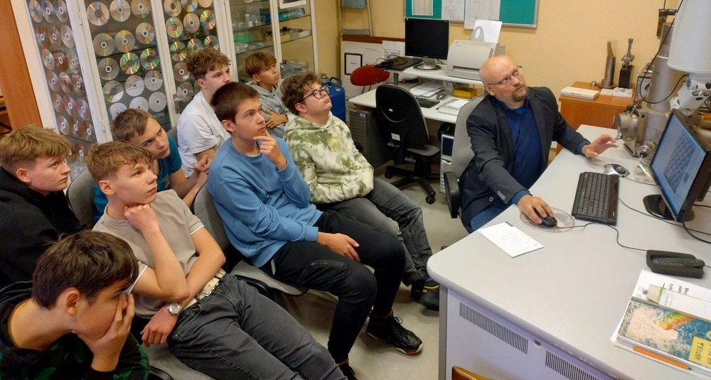 Uczniowie Szkoły Podstawowej nr 142 w Łodzi uczestniczą w zajęciach w laboratoriach Wydziału Fizyki i Informatyki Stosowanej Uniwersytetu Łódzkiego. Obserwują eksperymenty, mikroskopy i urządzenia do detekcji promieniowania kosmicznego, a prowadzący wyjaśniają zasady działania sprzętu i pokazują zastosowania fizyki w praktyce.