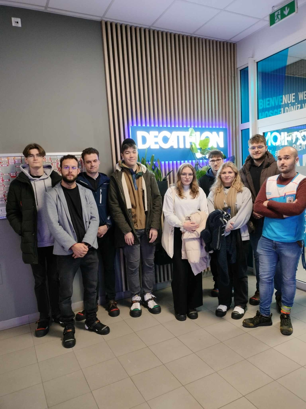 Grupa studentów stojąca pod logotypem firmy Decathlon