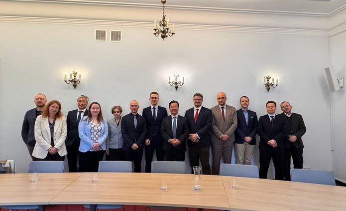 Zdjęcie grupowe grupy osób stojących przed stołem konferencyjnym na tle białej ściany