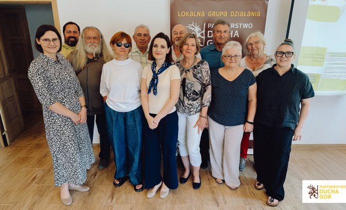 Grupa usmiechniętych osób pozująca razem do zdjęcia.